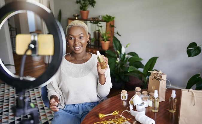 Woman presenting a product while filming a video on her smartphone