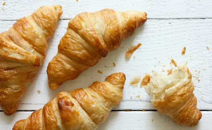 Photo of three croissants and some crumbs on a white background