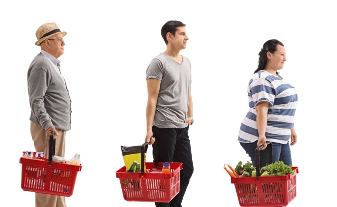 Three people of various ages in a grocery store shopping queue