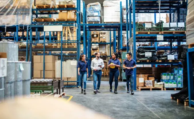 Group of four people walking through a warehouse.