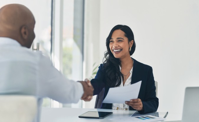 A new hire shakes the hand of her future employer. 