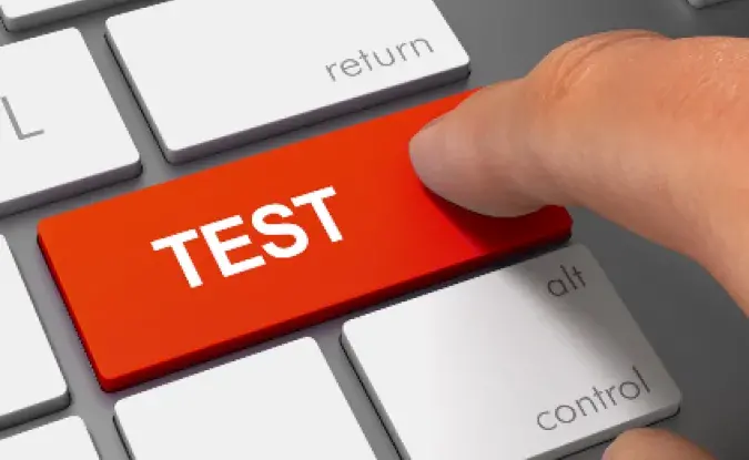 Red test button on a keyboard being pushed by an index finger