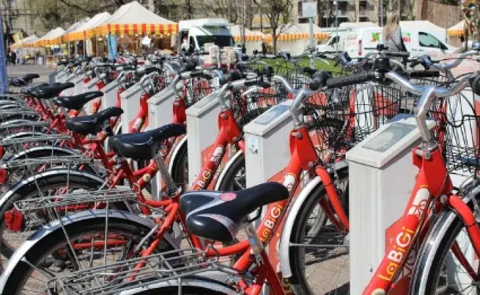 A row of red public share bicycles parked on a street