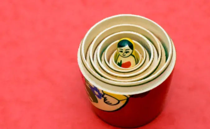 Nesting dolls, open and showing layers with one tiny doll in the center, on a red background