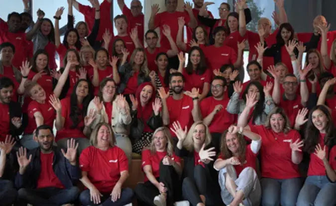 Large group of ethusiastic, smiling Kinaxis employees wearing red Kinaxis t-shirts