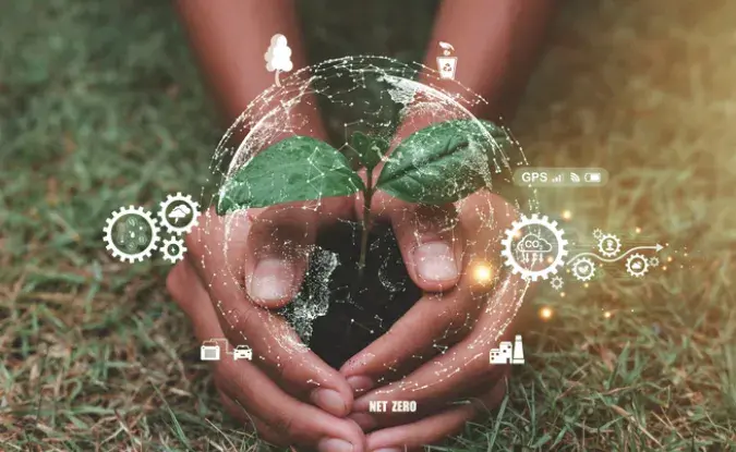 Stock photo of hands holding a small ball of soil with emerging plant sprout. Gear symbols surround the image with white graphics representing sustainable environmental energy green business goals.
