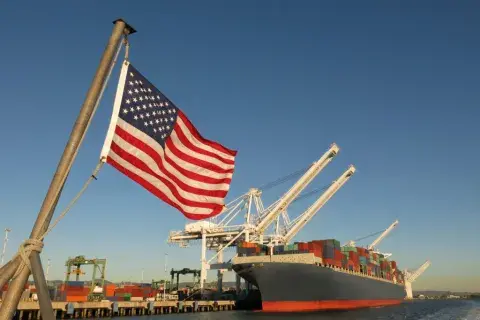 An American flag in front of a ship