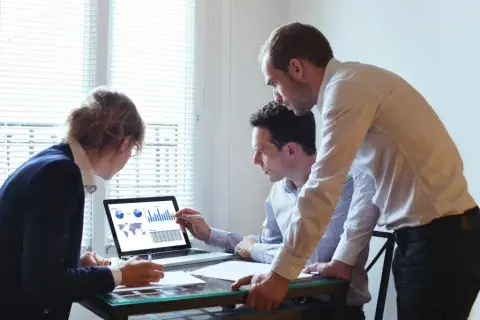Three people working and looking at a notebook with graphs on it