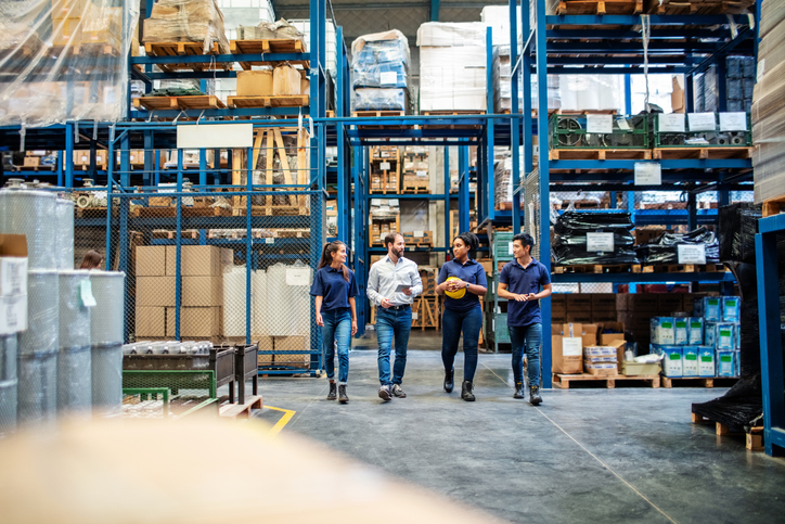 Group of four people walking through a warehouse.
