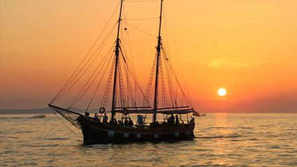 Classic sailing ship on the ocean at sunset